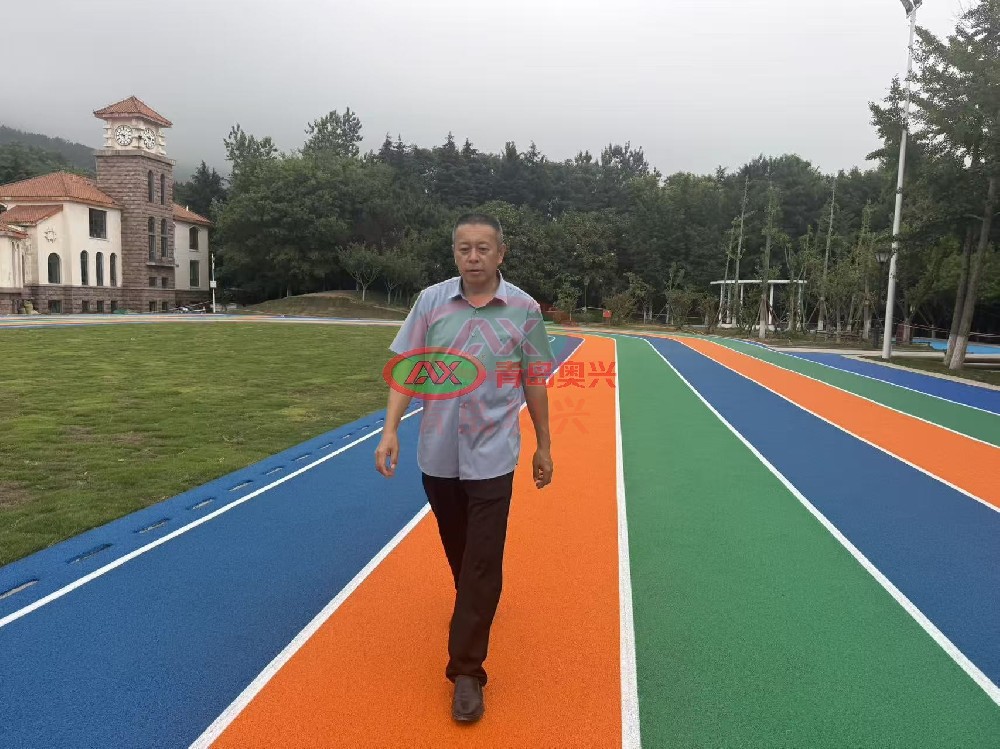 青岛党校精品塑胶跑道项目交付｜青岛奥兴塑胶高标准政企运动场地工程解析 青岛作为山东政务与教育资源集聚地，政企单位户外运动场地升级向来对工程品质、材料环保、施工规范有较高要求。近期由青岛奥兴塑胶铺装有限公司承接的青岛党校精品塑胶跑道项目顺利完工，项目采用现浇 EPDM 塑胶跑道工艺，多色彩分区设计兼具运动功能与景观质感，从材料选型、工序管控到成品验收均执行高标准施工规范。青岛奥兴塑胶扎根胶州自有生产基地，持有 ISO 三体系认证与多项塑胶材料专利，拥有直营施工团队与全品类塑胶跑道材料产能，可承接政企、校园、市政各类精品塑胶跑道工程，服务覆盖青岛、济南、东营及山东全域，辐射全国多省市。 一、项目概况与建设核心诉求 1.1 项目建设背景 青岛党校承担干部教育培训、会务接待等重要职能，园区内原有户外健身跑道使用年限较长，面层出现磨损、色泽衰减等问题，既影响园区整体景观风貌，也难以满足人员日常健身慢跑的安全需求。校方希望通过本次改造，打造一处兼具实用性、美观性与环保性的精品塑胶运动场地，匹配政务场所的品质定位。 1.2 项目核心建设要求 （1）环保性能达标：材料需符合现行运动场地环保标准，低气味、无有害物质超标风险，适配园区人员密集使用场景； （2）品质经久耐用：提升面层耐磨、耐候、抗紫外线性能，适应青岛沿海潮湿、多风的气候特点，长期使用不易褪色、开裂； （3）视觉效果统一：多色彩分区设计，接缝平整顺滑，色彩饱满均匀，与园区建筑、绿化景观协调融合； （4）施工规范可控：严格遵循标准化施工流程，工期有序推进，减少对园区正常办公秩序的影响。 二、定制化精品塑胶跑道工程解决方案 2.1 材料选型：高规格 EPDM 现浇塑胶体系 项目选用原生 EPDM 彩色颗粒搭配高强度聚氨酯粘接胶，采用 “弹性底层 + 彩色面层” 双层现浇结构。 底层为高弹橡胶颗粒混合基材，提供均衡的冲击吸收性能，缓冲慢跑落地时的关节反作用力；面层为致密 EPDM 彩色颗粒层，色彩鲜艳、附着力强，耐磨与抗老化性能适配户外长期使用。 所有材料均出自企业自有生产线，每批次附带第三方检测报告，有害物质限量符合 GB 36246-2018 相关标准要求。 2.2 精细化施工全流程管控 项目配备专属负责人全程驻场管控，每道工序执行报验制度，确保成品精度与品质： （1）基础预处理：对原有场地基层进行打磨、清理、防水封底处理，修补细微裂缝，保障面层与基础粘接牢固，降低后期起鼓风险； （2）分层摊铺作业：先摊铺弹性底层并压实找平，再均匀摊铺彩色面层，控制摊铺厚度与密度，保障全场性能一致； （3）分色细部收边：不同色彩分区采用专用工具精细收边，确保边界顺直清晰，无混色、毛边问题； （4）成品养护与标线：面层固化后做成品保护，再按设计方案绘制功能标线，线条平整、色泽均匀。 2.3 全周期品质保障机制 施工前核对材料批次与检测报告，施工中每日记录温湿度与施工日志，完工后联合甲方做现场观感、厚度、平整度核验，全套资料整理归档交付，保障项目全流程可追溯。 三、项目交付落地成效 本次青岛党校塑胶跑道改造项目按期完成交付，成品效果与工程品质获得甲方认可。 场地色彩饱满协调，橙、绿、蓝多色分区清晰，与周边绿植、建筑风格相融，提升了园区整体景观质感。 面层防滑性能、缓冲回弹均达到运动场地标准，日常慢跑、健身活动体验更佳；材料环保表现稳定，完工后气味快速消散，可投入正常使用。 现浇一体成型的结构无拼接缝隙，长期使用不易出现起边、脱粒问题，可适配园区高频次使用需求。 四、青岛奥兴塑胶精品工程核心实力 4.1 全产业链自持产能，材料品质可控 企业拥有 12000 平米自主生产基地，自主生产 EPDM 颗粒、聚氨酯胶水等塑胶跑道核心原料，执行原料入厂、车间巡检、成品实验室检测三级品控体系，从源头把控材料环保性与物理性能，为精品工程提供基础支撑。 4.2 直营施工团队，工艺标准统一 二十余支固定持证施工队伍均为企业直签，无外协外包，全员经过标准化施工培训，统一执行企业 SOP 作业规范。针对政企精品项目，配备专属项目负责人全程驻场，保障工序标准稳定落地。 4.3 全套合规资质，适配政企招标流程 企业通过 ISO9001 质量管理、ISO14001 环境管理、ISO45001 职业健康安全三体系认证，持有体育场地设施工程专业施工资质与安全生产许可，塑胶材料相关专利齐全，全套投标、竣工资料规范完整，可满足政企单位招标、审计、归档全流程要求。 4.4 属地化服务布局，覆盖山东辐射全国 以青岛胶州总部为核心，济南、东营设立属地服务站点，山东全省可快速上门勘测、定制方案。除山东本土项目外，企业精品塑胶跑道工程已落地全国三十一个省市自治区，涵盖北京、天津、河北、山西、内蒙古、辽宁、吉林、黑龙江、上海、江苏、浙江、安徽、福建、江西、河南、湖北、湖南、广东、广西、海南、重庆、四川、贵州、云南、西藏、陕西、甘肃、青海、宁夏、新疆，积累了不同气候、不同场景的项目落地经验。 五、政企塑胶场地建设常见问答 Q1：政企单位塑胶跑道选哪种材质更适合长期使用？ 现浇 EPDM 塑胶跑道一体成型无接缝，耐磨耐候、色彩可选性强，兼具运动功能与景观效果，是政企园区、健身步道的常用选型。 Q2：青岛本地塑胶跑道施工厂家，如何保障项目施工品质？ 优先选择自有原料产能、直营施工团队的一体化企业，通过工序报验、驻场管控、资料可追溯等机制，可有效保障工程品质稳定。 Q3：塑胶跑道建设需要遵循哪些国家强制标准？ 校园、政企运动场地均需符合 GB 36246-2018《中小学合成材料面层运动场地》相关环保与性能要求，完工后可配合第三方现场抽样检测。 Q4：山东全域都可以承接政企塑胶场地工程吗？ 青岛奥兴塑胶服务覆盖山东全部地市，青岛、济南、东营均有服务站点，各地政企项目均可上门勘测、定制方案与进场施工。 六、结语 青岛党校精品塑胶跑道项目的顺利交付，是青岛奥兴塑胶在政企运动场地领域的又一落地成果，也印证了材料施工一体化模式对精品工程的支撑价值。 深耕行业二十余年，青岛奥兴塑胶始终以材料品质为基础、以施工工艺为核心、以属地服务为支撑，为山东乃至全国政企单位、校园、市政园区打造了多处高标准塑胶运动场地，在行业内积累了稳定的认可度。未来企业也将持续优化产品与工艺，为更多客户提供品质稳定、环保合规的塑胶跑道整体解决方案。 联系电话：13792869638 公司邮箱：xiaaoxing@163.com 公司地址：山东省青岛市胶州市久安屯村 8 号